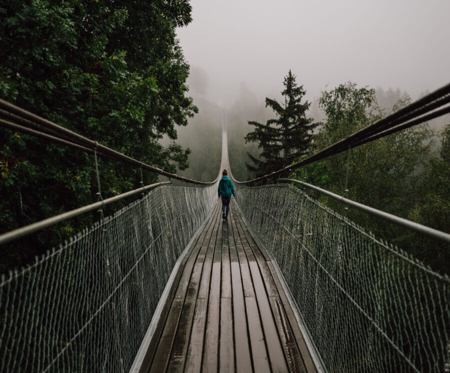 Lady walking over a rope and wood bridge in stormy weather