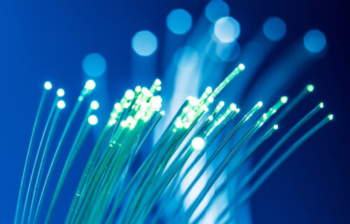 Bundle of optical fibers with lights in the ends. Blue background.